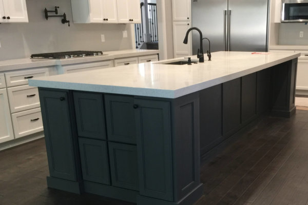 A kitchen with custom design, including a large island and white cabinets.