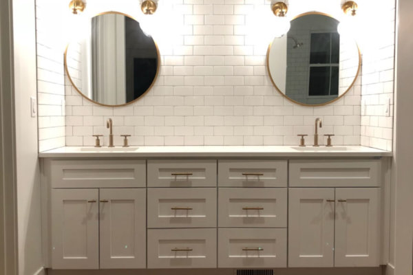 White-tiled bathroom with a rug on the floor.