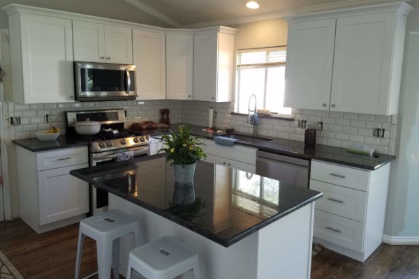 Modern kitchen featuring white cabinets and black counters.