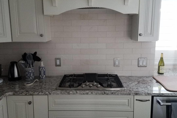 Contemporary kitchen with white cabinets and stove top.