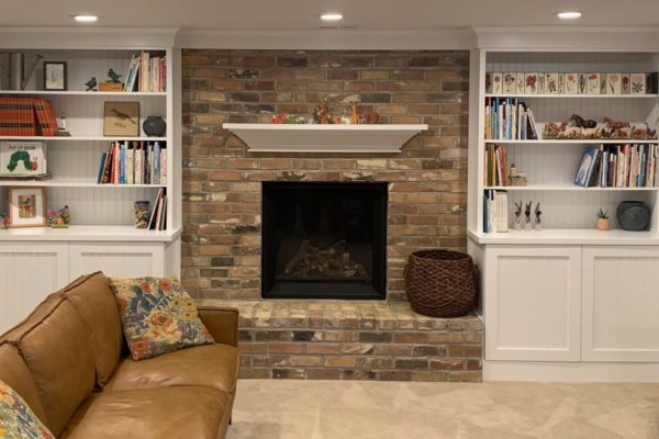 Warm living room featuring brick fireplace and bookshelves.