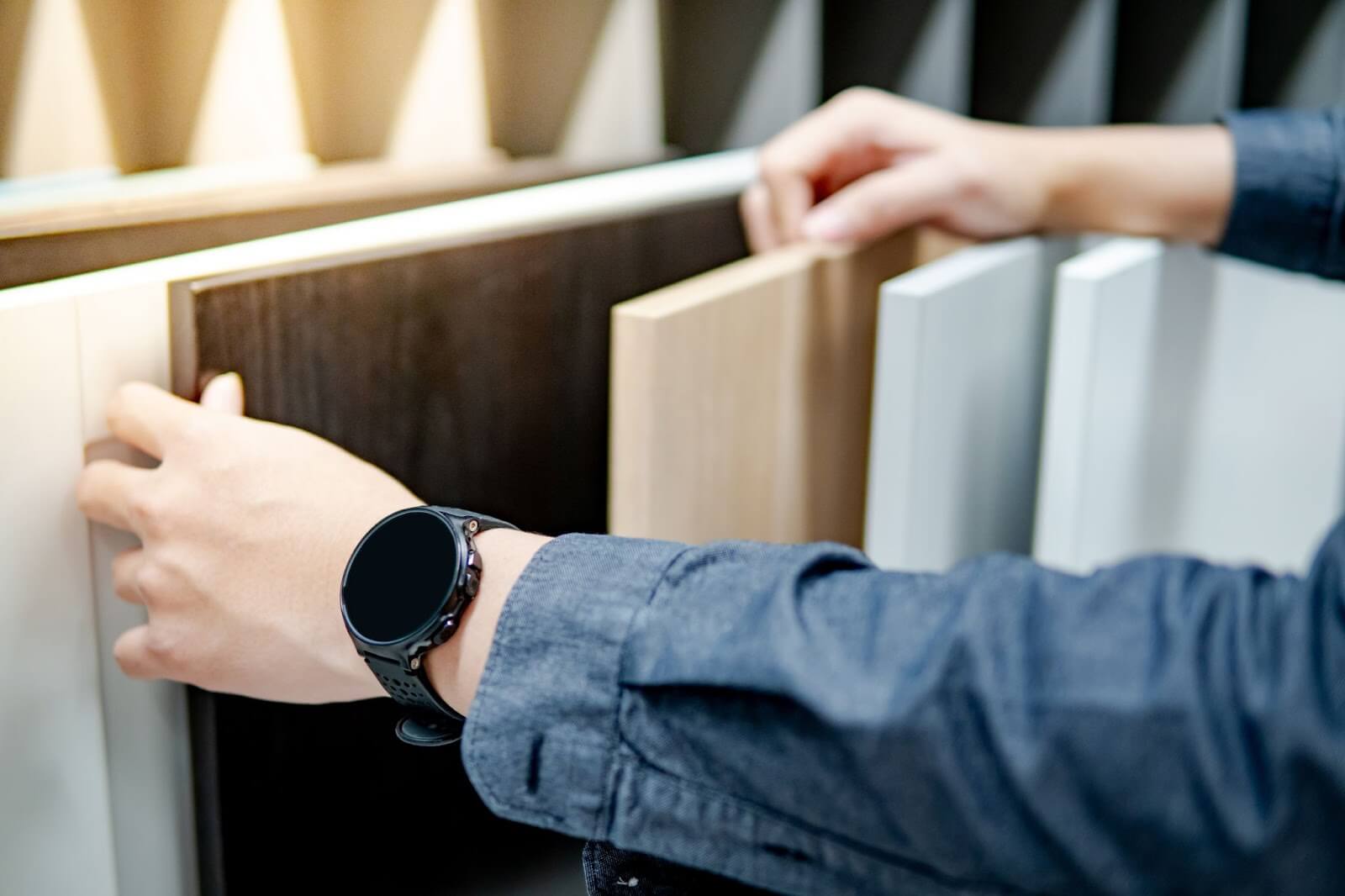 A man holding a watch while examining a piece of wood. Relevant to modern cabinets, custom cabinets, and cabinet design.