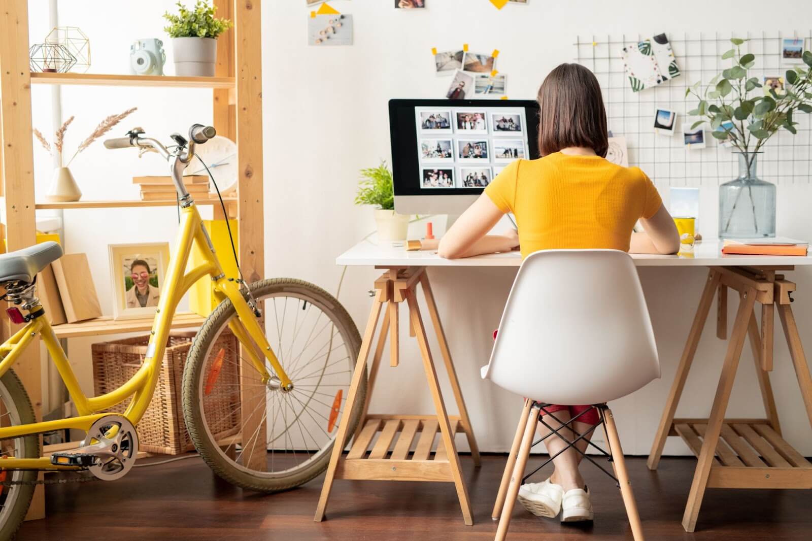 A woman at a desk in a home office, with custom cabinets and a bicycle visible in the background.