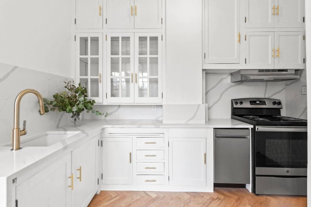 A stylish white kitchen featuring gold hardware and marble countertops for a refined look