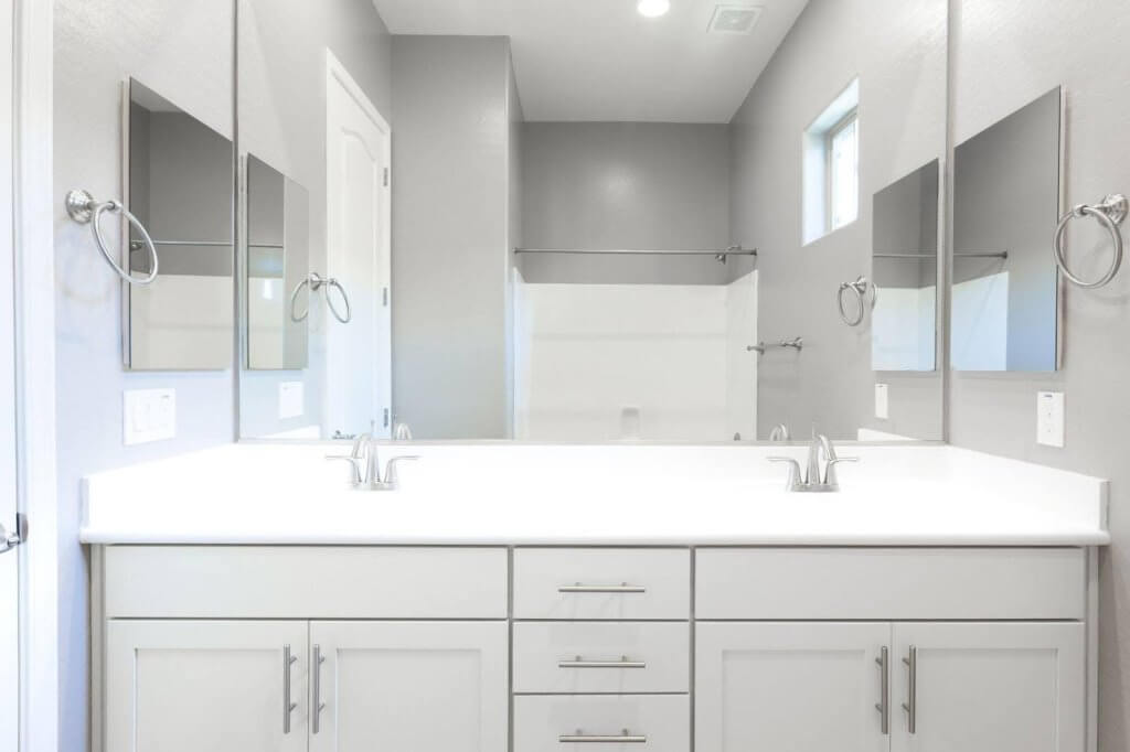 A clean bathroom featuring white cabinets and a double sink showcasing a modern and organized design