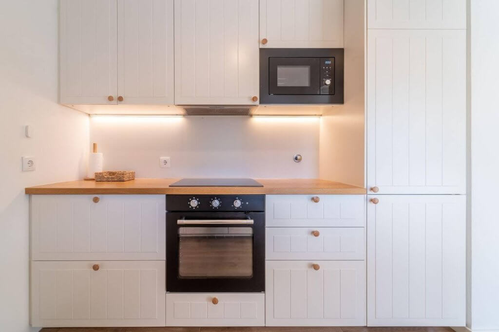 A modern kitchen featuring white cabinets and a microwave on the countertop