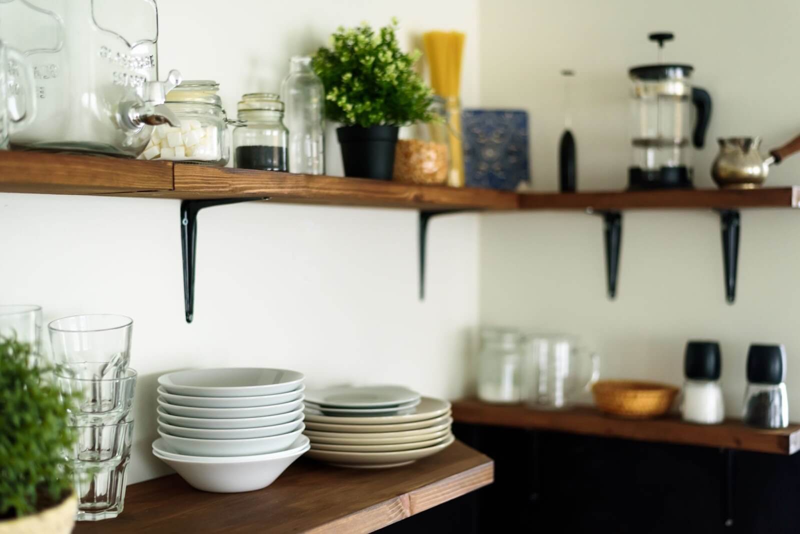 Wooden kitchen shelves with dishes, plants, and kitchenware.
